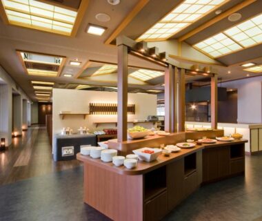Wooden buffet counter with arranged dishes and warm traditional dining interior at Meijikan in Shizuoka, Chūbu