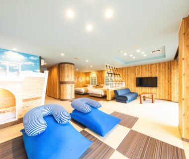Spacious wooden relaxation lounge with blue reclining chairs and seating at Meijikan ryokan in Shizuoka
