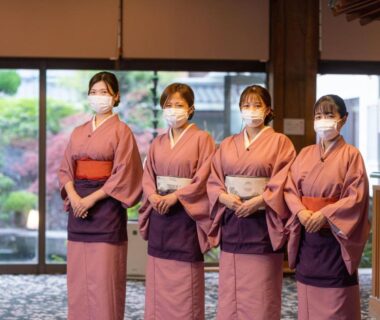 Four masked attendants in matching kimono standing in ryokan lobby with garden view Meitei no Yado Hotel Koshien Yamanashi