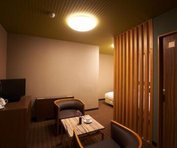 Low table with chairs, wooden partition and bed in Meitoya So guest room, Yamagata Tohoku Japan