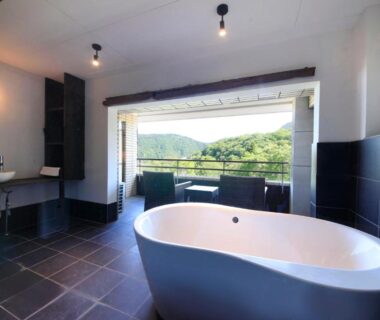 Freestanding tub in modern tiled room at Merveille Hakone Gora with balcony and green mountain view in Kanagawa