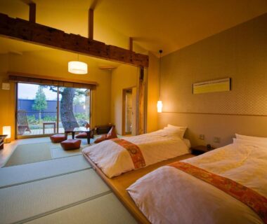 Tatami room with futons, low table, sliding doors opening to a garden view at Migiwaya in Shizuoka