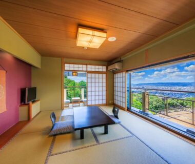 Tatami room with low table and shoji screens overlooking city and valley at Mikasa ryokan in Nara, Kansai