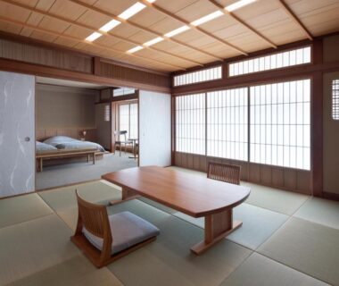 Traditional tatami room with low wooden table, floor chairs, shoji screens and adjoining futon sleeping area