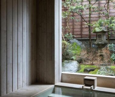 Tiled indoor bath with window looking out to a quiet stone and moss garden at Mikuniya in Hyōgo