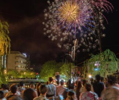 Yukata-clad crowd watching riverside fireworks near Mikuniya in Hyōgo Kansai at night