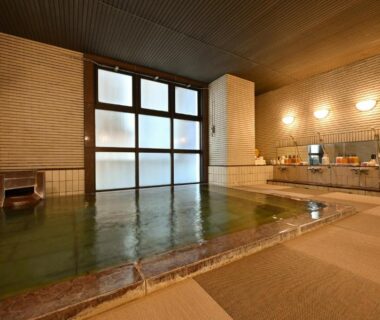 Spacious tiled indoor onsen with water spout and frosted windows at Mimatsukan, Gunma