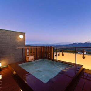 Rooftop outdoor onsen bath on wooden deck at dusk with distant mountain views, Mimatsukan in Gunma