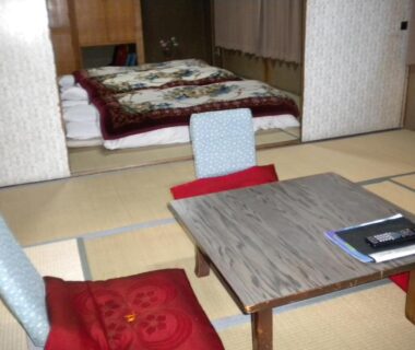 Tatami room with low table, floor cushions and folded bedding at Mimatsuso Ryokan in Hokkaidō