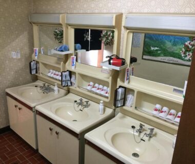 Three washbasins with mirrors, toiletries and vintage cabinets at Mimatsuso Ryokan wash area in Hokkaidō