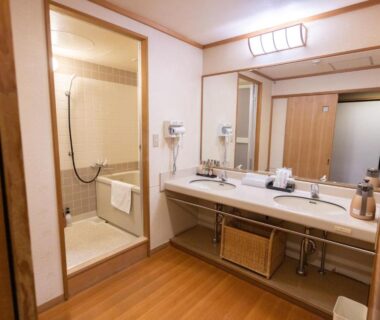 Double-sink vanity with large mirror and tiled shower room at Minakami Hotel Juraku in Gunma