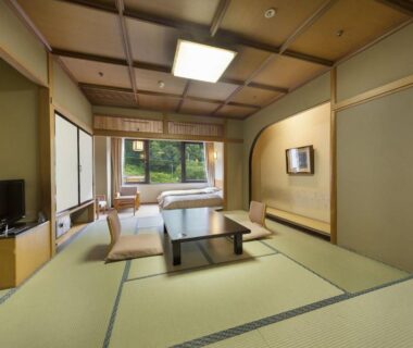 Traditional tatami room with low table, floor cushions, shoji screens and garden view at Minakami Hotel Juraku, Gunma