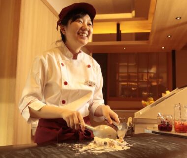 Smiling chef slicing ingredients at ryokan kitchen counter, Minakami Hotel Juraku, Gunma, Kantō, Japan