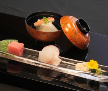 Black lacquer tray with delicate Japanese small dishes on a glass plate and a lidded lacquer bowl at Minakamisansou, Gunma