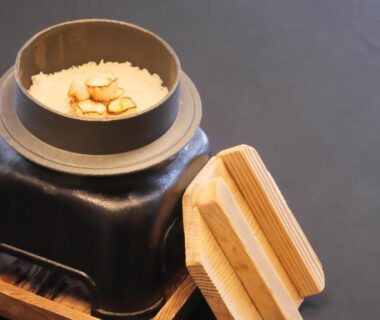 Donabe clay pot of cooked rice with garnish beside wooden lid at Minakamisansou, Gunma, Kantō