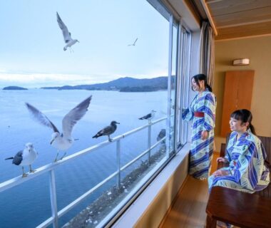 Two guests in yukata in tatami room by window with seagulls over sea at Minami Sanriku Hotel kanyo Miyagi