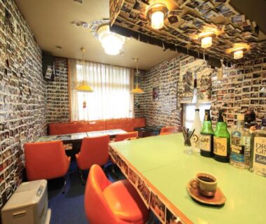 Retro lounge with green counter, orange chairs and walls covered in photos at Minshuku Fukufuji, Tochigi