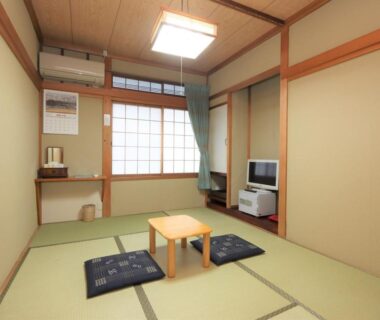 Traditional tatami room with low table, zabuton cushions and shoji screen at Minshuku Iwatakan in Gifu