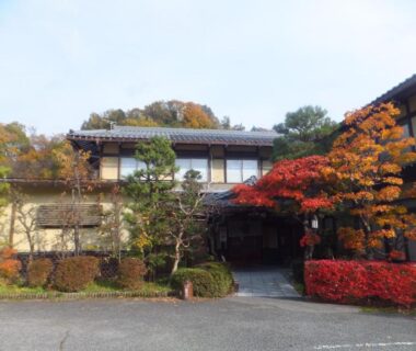 Two-story entrance framed by red maple at Minshuku Iwatakan in Gifu, Chubu