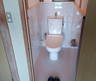 Narrow toilet room with Western toilet and slippers at entrance in Minshuku Kamagari Hiroshima