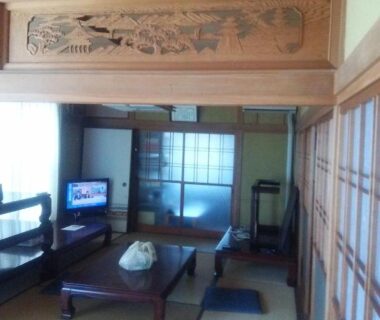 Tatami room with low table, zabuton cushions, shoji screens and carved transom at Minshuku Kamagari Hiroshima