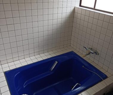 Compact blue tiled bathtub with faucet and window in a tiled bathroom at Minshuku Kamagari, Hiroshima