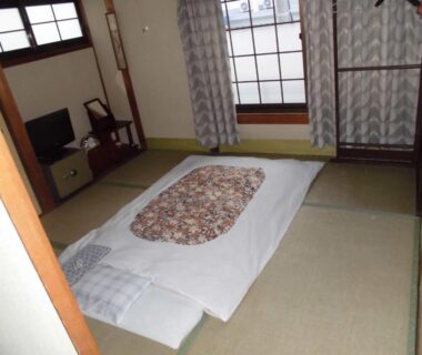 Futon on tatami floor with shoji screens and low TV cabinet in Minshuku Katsuya, Wakayama
