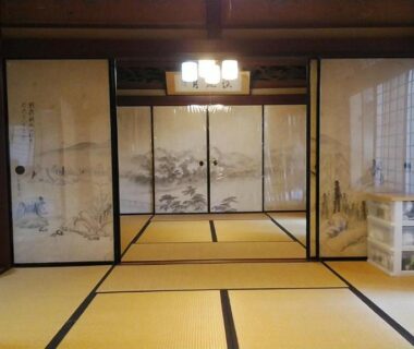 Traditional tatami room with painted fusuma panels, shoji screens and low seating at Minshuku Kitamaebune in Ishikawa