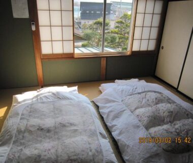 Two futon mattresses on tatami by shoji window overlooking garden at Minshuku Kobayashi in Yamanashi