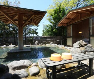 Outdoor onsen bath with wooden stools and shelter at Minshuku Miyama, Nagano