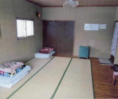 Tatami room with folded futons, window and simple furnishings at Minshuku Mutsukari, Hokkaidō