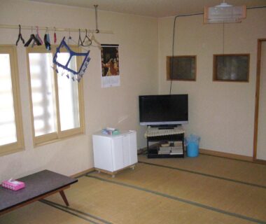 Traditional tatami room with low table, television, small fridge and drying rack at Minshuku Mutsukari, Hokkaidō