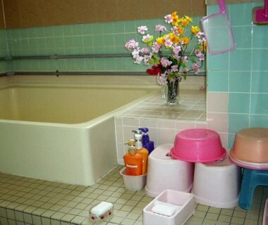 Tiled bath area with stools, wash basins, toiletries and floral arrangement at Minshuku Mutsukari, Hokkaidō