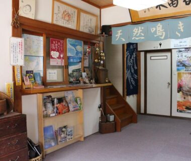 Small reception area with wooden counter, brochures and staircase, Minshuku Oe, Kyoto Kansai