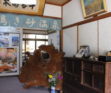 Traditional ryokan lobby with large wooden sculpture, cabinets and entrance windows at Minshuku Oe Kyoto