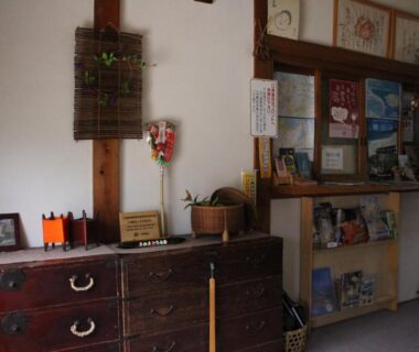 Low wooden chest and brochure shelf in Minshuku Oe reception area Kyoto Kansai
