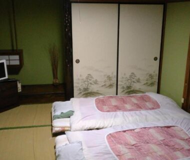 Traditional tatami room with futon bedding, shoji, painted sliding doors and small television at Minshuku Takahashi Kashibuneten in Shizuoka