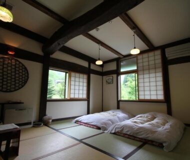 Traditional tatami room with futon bedding, shoji screens and exposed wooden beams at Minshuku Takizawa in Gifu