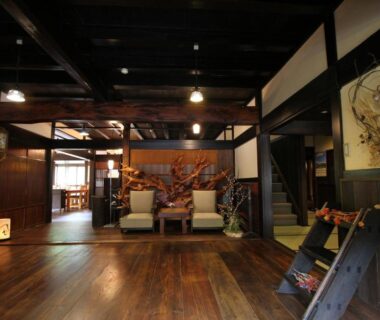 Polished wooden floors and exposed beams in Minshuku Takizawa lobby with warm seating and shoji screens, Chūbu Gifu
