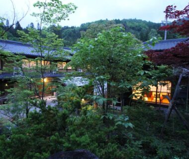 Lantern-lit garden courtyard with traditional wooden ryokan rooms at Minshuku Takizawa, Gifu