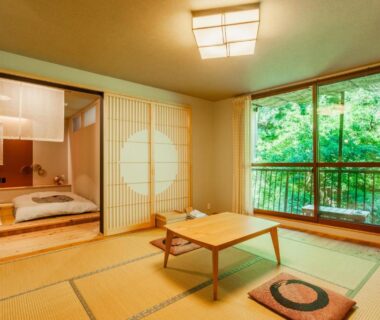 Tatami room with low table, futons beyond shoji and lush garden view at Misenkan Nara