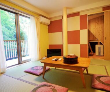 Tatami mat room with low wooden table, cushions and balcony doors at Misenkan in Nara, Kansai