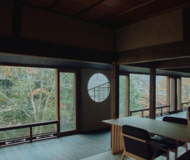 Large wooden room with low tables and circular window overlooking autumn maples at Misenkan, Nara, Kansai