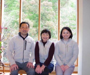 Three people seated in ryokan lobby with large window and floral arrangement, Misenkan Nara