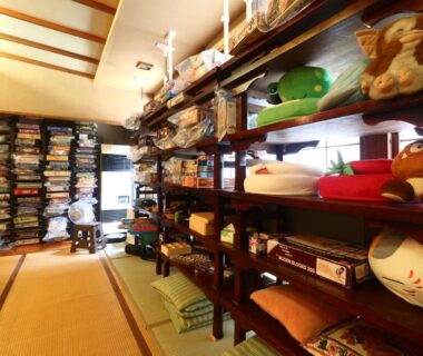 Shelves of folded futons, cushions and plush toys on tatami floor in Mitake ryokan, Kanagawa, Kantō