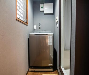 Compact washing machine in narrow corridor at Mitomi Inn, Tokyo, Kantō, Japan
