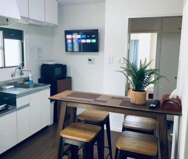 Compact kitchenette with wooden dining table and stools at Mitomi Inn, Tokyo, Kantō, Japan