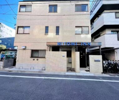 Beige tiled exterior and entrance of Mitomi Inn on a Tokyo street