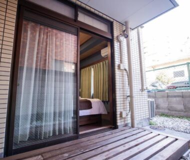 Wooden veranda and sliding glass door leading to Mitomi Inn guest room in Tokyo residential setting