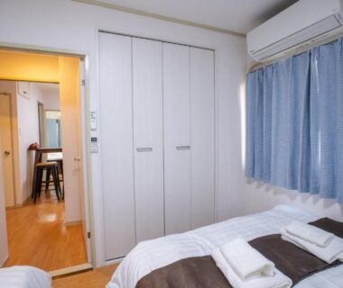 Twin bedroom with two beds, folded towels, closet and air conditioner at Mitomi inn Tokyo
